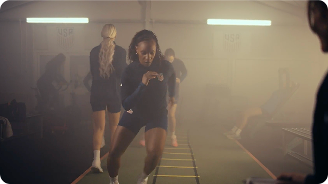 Former U.S. Soccer player Crystal Dunn is training by running ladders with other players. An overlay with a play video button appears in the corner.