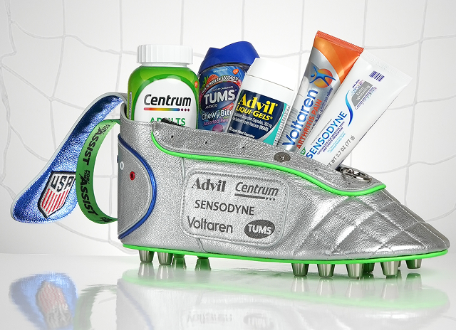 A custom blue, silver, and green dopp kit shaped like a soccer cleat containing Centrum, TUMS, Advil, Sensodyne, and Voltaren products. More info at haleonassist.com. Disclaimer says Some products may contain NSAIDs and/or Acetaminophen and should not be taken together. Please review labels and use as directed.