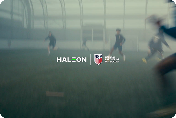 U.S. Soccer players train together on a field. An overlay with a play video button appears in the corner.